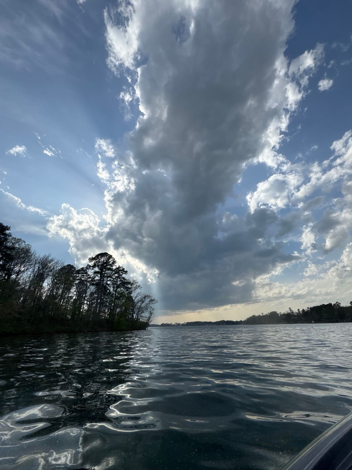 Storm clouds and sunbeams over an Arkansas lake, seen from a boat